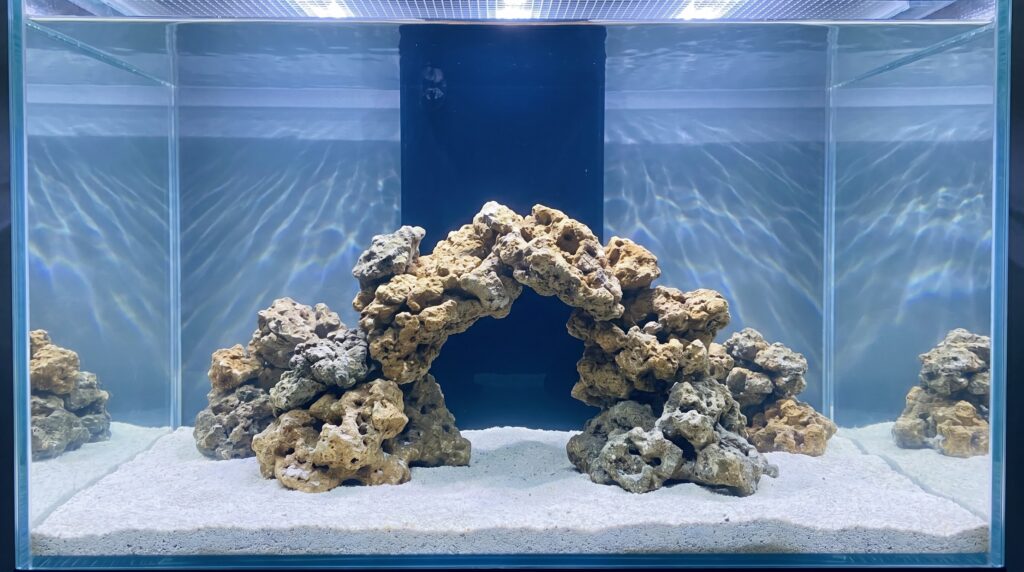 Freshly aquascaped reef tank with porous live rock and white sand before cycling